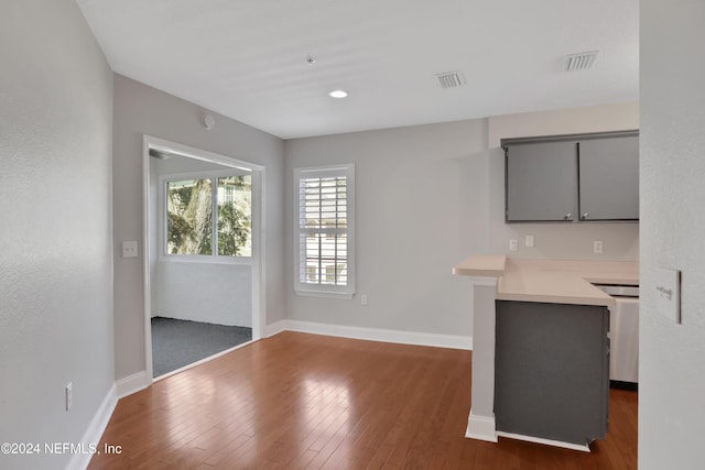 kitchen with kitchen peninsula, gray cabinets, and dark hardwood / wood-style flooring