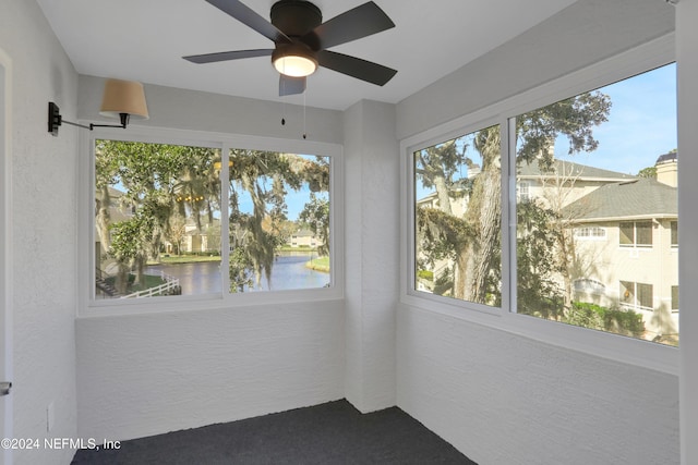 unfurnished sunroom with a water view and ceiling fan