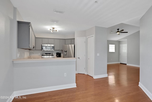 kitchen featuring appliances with stainless steel finishes, light hardwood / wood-style flooring, gray cabinetry, sink, and kitchen peninsula