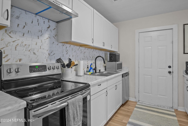 kitchen with backsplash, stainless steel appliances, extractor fan, sink, and white cabinetry