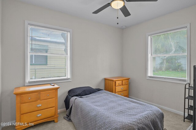 carpeted bedroom featuring multiple windows and ceiling fan