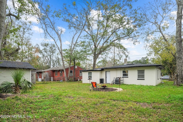 back of house featuring a yard and a fire pit