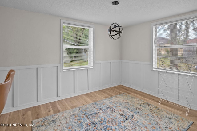 unfurnished dining area featuring a textured ceiling and light hardwood / wood-style flooring