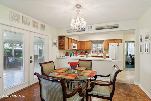 dining area with dark parquet floors, a chandelier, and sink