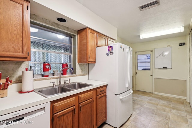 kitchen featuring light tile patterned floors, white appliances, and sink