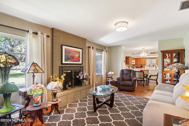 living room with a wealth of natural light, a chandelier, and a brick fireplace