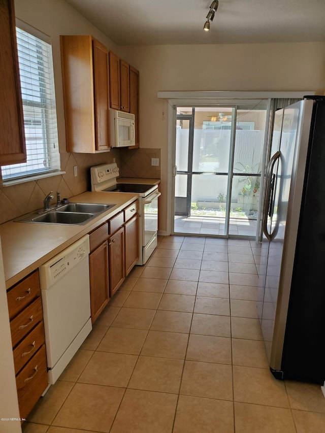 kitchen with white appliances, track lighting, sink, light tile patterned floors, and tasteful backsplash