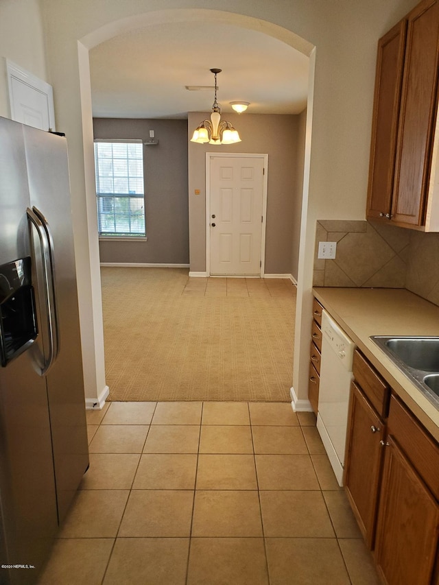 kitchen featuring stainless steel fridge, white dishwasher, pendant lighting, an inviting chandelier, and light tile patterned flooring