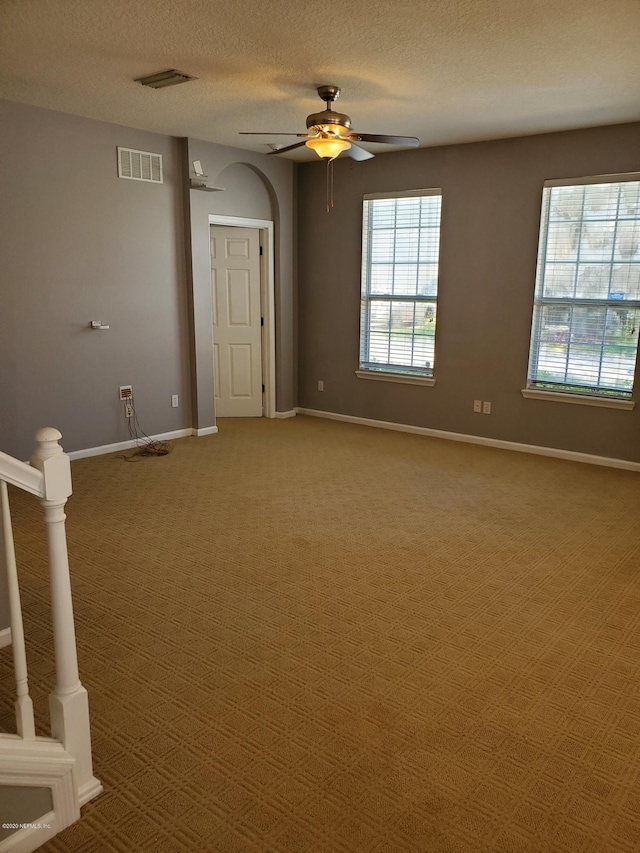 carpeted spare room with ceiling fan and a textured ceiling