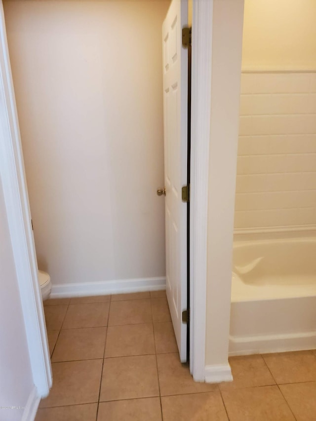 bathroom featuring tile patterned flooring, a bath, and toilet