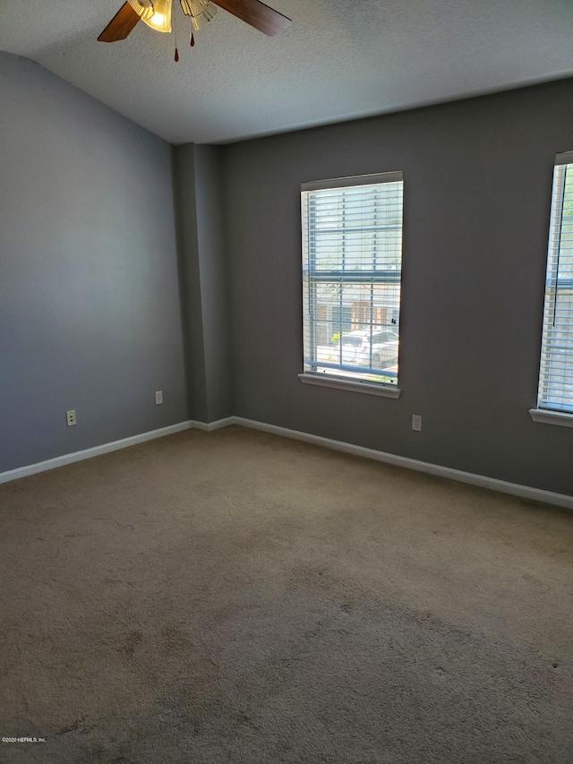 carpeted spare room featuring ceiling fan, a textured ceiling, and vaulted ceiling