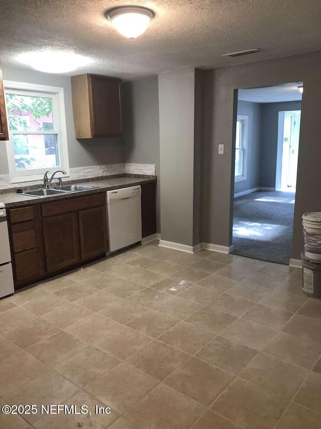 kitchen featuring a textured ceiling, white dishwasher, a healthy amount of sunlight, and sink