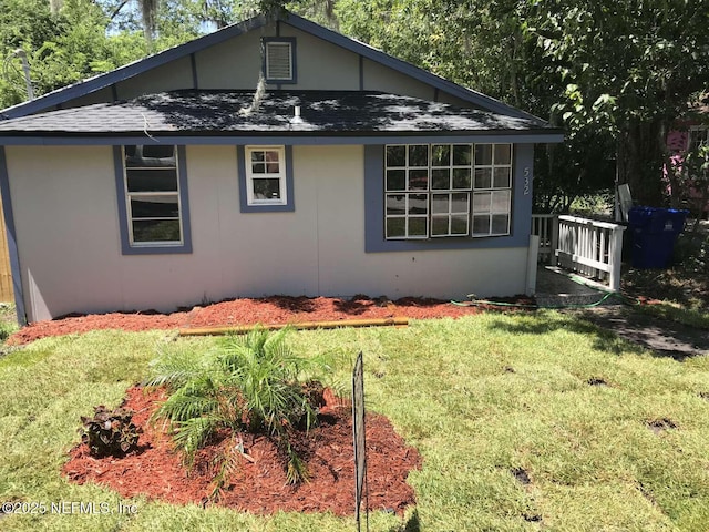 bungalow-style house with roof with shingles, a front lawn, and stucco siding