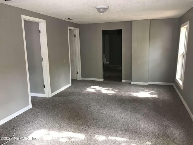 unfurnished room with a textured ceiling, carpet, and baseboards