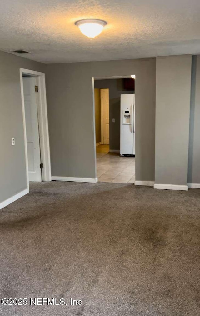 spare room with carpet floors, a textured ceiling, and baseboards