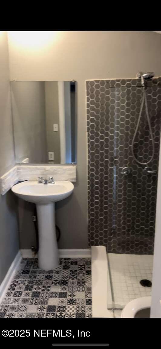 bathroom with a shower stall, baseboards, and tile patterned floors