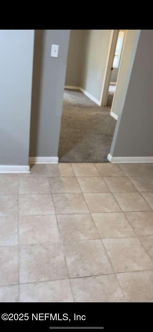 unfurnished room with carpet floors, baseboards, and tile patterned floors