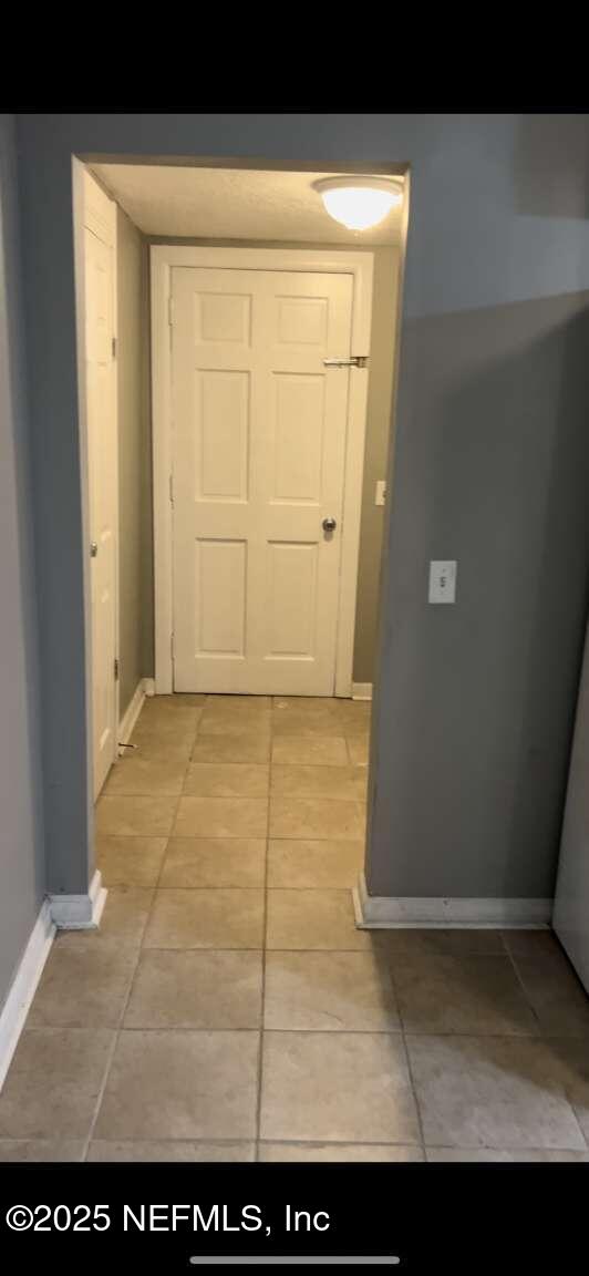 corridor with light tile patterned floors and baseboards