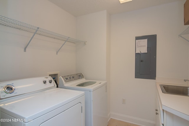 laundry area featuring washing machine and dryer, light tile patterned floors, sink, and electric panel