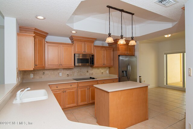 kitchen featuring hanging light fixtures, a textured ceiling, a tray ceiling, a kitchen island, and appliances with stainless steel finishes