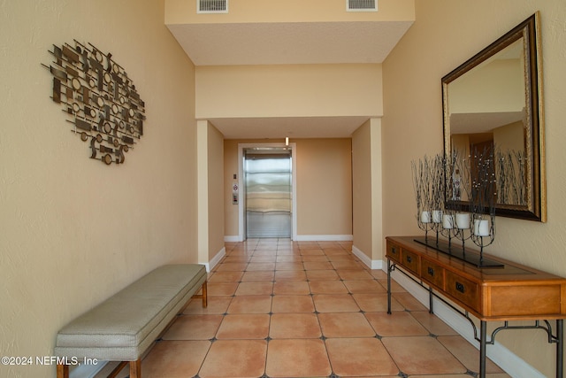 corridor with light tile patterned floors and a textured ceiling