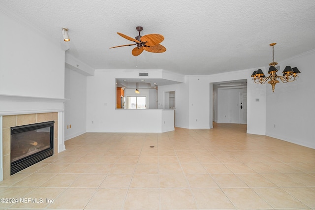 unfurnished living room with ornamental molding, ceiling fan with notable chandelier, a textured ceiling, light tile patterned floors, and a tiled fireplace