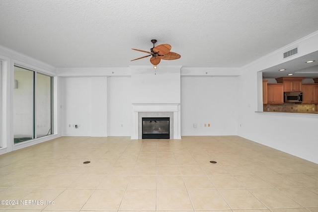 unfurnished living room with light tile patterned floors, a textured ceiling, ceiling fan, and ornamental molding