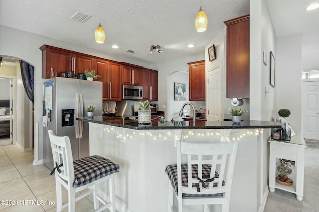 kitchen with appliances with stainless steel finishes, a textured ceiling, and hanging light fixtures