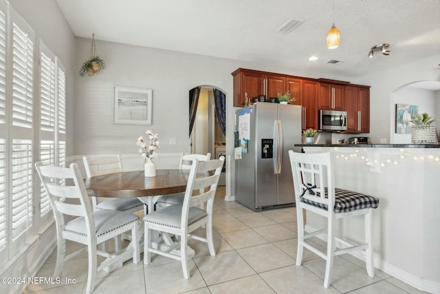 kitchen featuring decorative light fixtures, light tile patterned floors, a textured ceiling, and appliances with stainless steel finishes