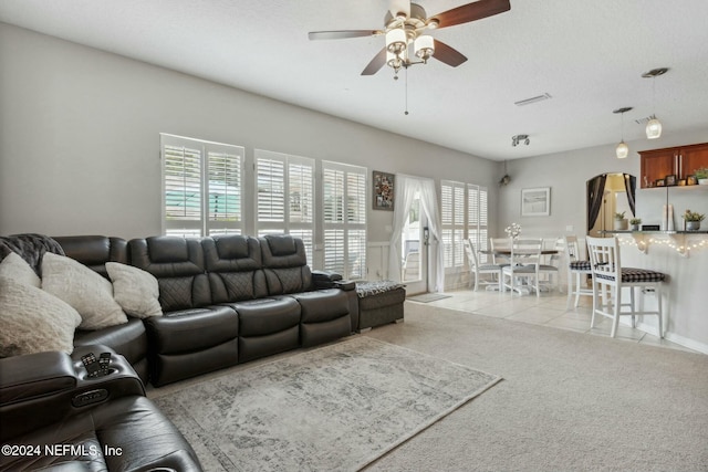 living room featuring a textured ceiling, light colored carpet, and plenty of natural light