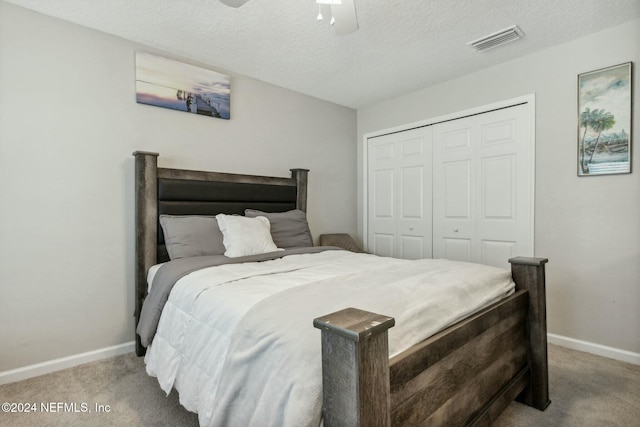 bedroom featuring a textured ceiling, light colored carpet, and ceiling fan