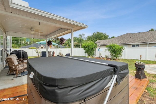 view of patio featuring ceiling fan, grilling area, a wooden deck, and a hot tub