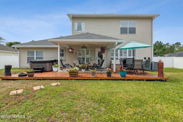 back of house featuring a lawn, a hot tub, and a deck