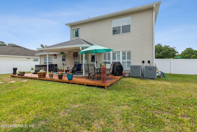 back of property featuring central air condition unit, a wooden deck, a lawn, and a hot tub