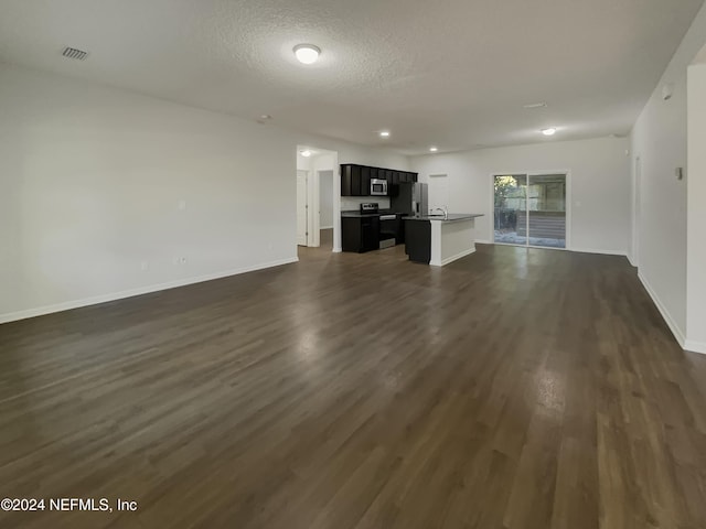 unfurnished living room with a textured ceiling, sink, and dark wood-type flooring