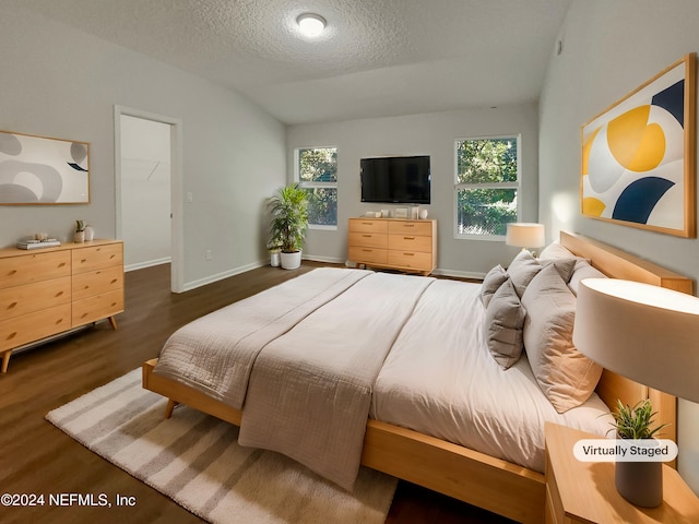 bedroom with a textured ceiling, dark hardwood / wood-style flooring, and lofted ceiling