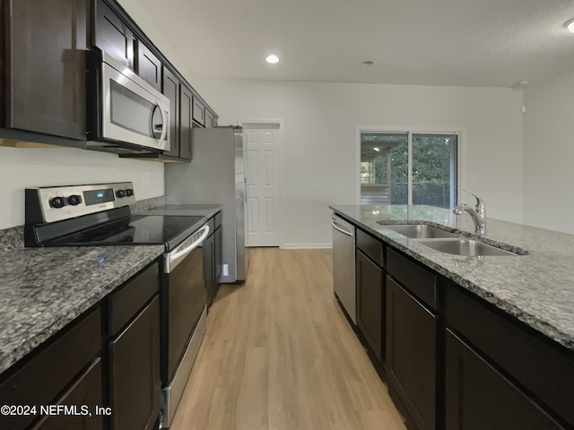 kitchen with sink, stainless steel appliances, dark stone countertops, light hardwood / wood-style floors, and dark brown cabinets