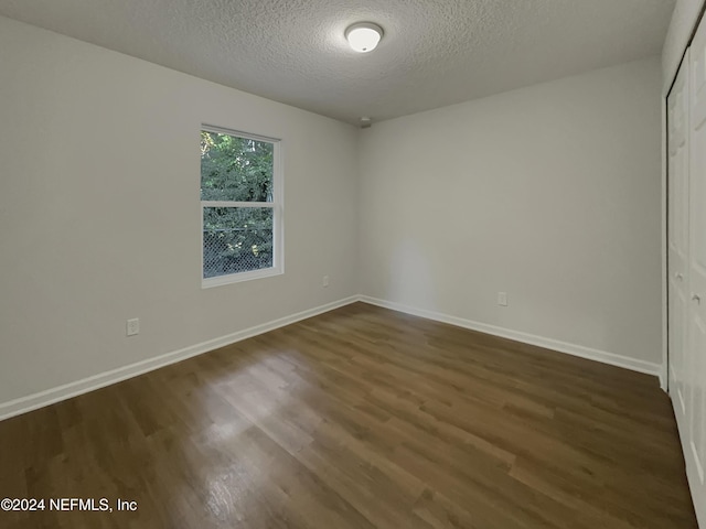 spare room featuring dark hardwood / wood-style floors and a textured ceiling