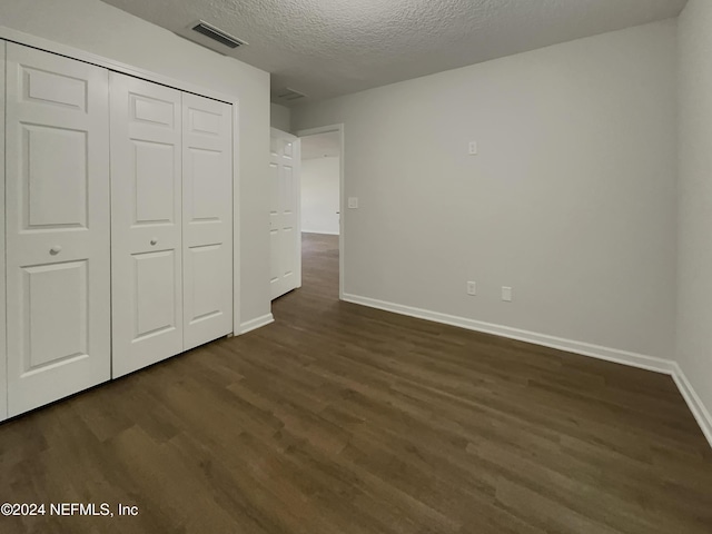 unfurnished bedroom with a closet, dark hardwood / wood-style floors, and a textured ceiling