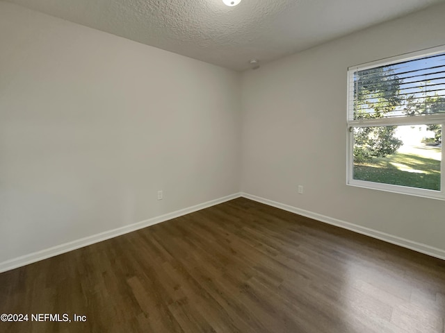 spare room featuring a textured ceiling and dark hardwood / wood-style floors