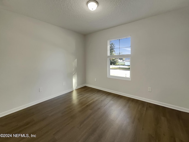 unfurnished room featuring a textured ceiling and dark hardwood / wood-style floors