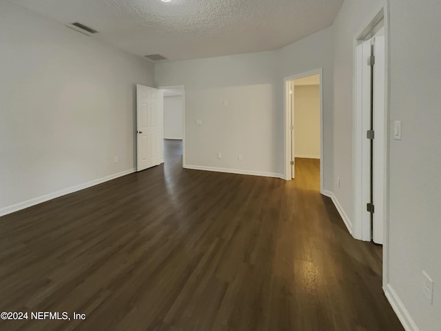 unfurnished room featuring a textured ceiling and dark hardwood / wood-style floors