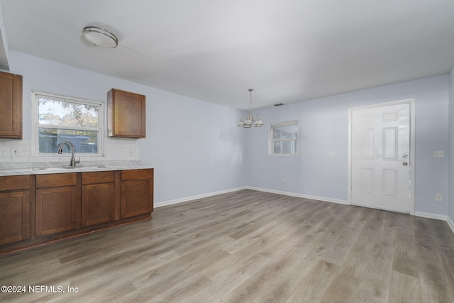 kitchen featuring pendant lighting, light wood-type flooring, tasteful backsplash, and sink