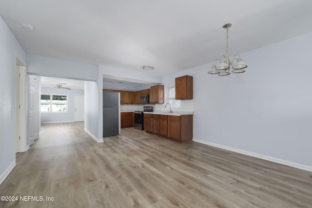 kitchen with ceiling fan with notable chandelier, sink, hanging light fixtures, light hardwood / wood-style flooring, and stainless steel appliances