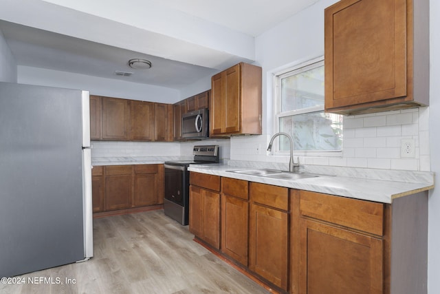 kitchen featuring tasteful backsplash, light hardwood / wood-style flooring, stainless steel appliances, and sink