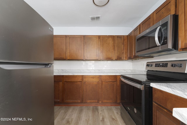 kitchen featuring decorative backsplash, stainless steel appliances, and light hardwood / wood-style floors