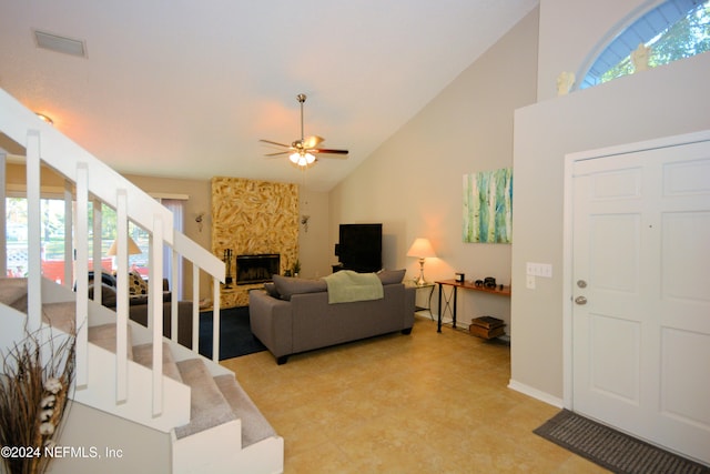 living room featuring ceiling fan, a fireplace, and high vaulted ceiling