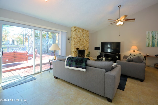 living room with ceiling fan, light tile patterned flooring, lofted ceiling, and a fireplace