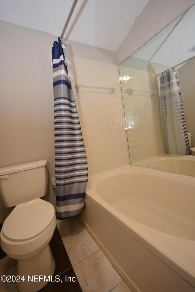 bathroom featuring tile patterned flooring, shower / bath combination with curtain, and toilet