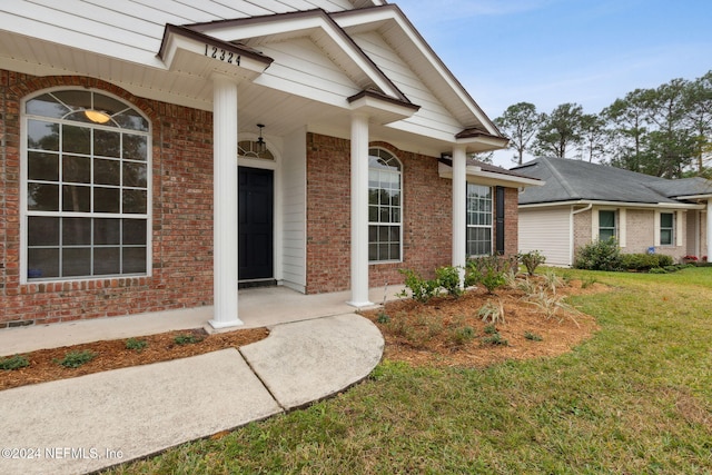 doorway to property with a yard and a porch